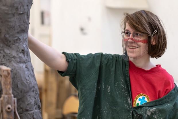 Uśmiechnięta dziewczyna rzeźbi w glinie